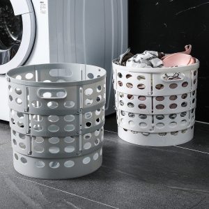 Hai giỏ đựng quần áo màu trắng và xám đặt cạnh máy giặt, một giỏ đã có quần áo bên trong.
