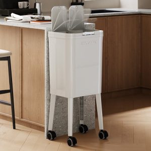 Thùng rác màu trắng cao, có bánh xe, đặt sát bàn bếp, nắp mở tiện lợi.