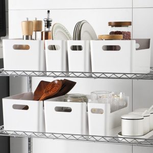 Các hộp nhựa trắng đựng đồ dùng nhà bếp trên kệ inox.
