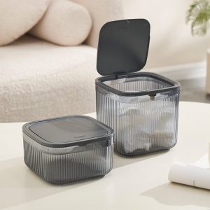 Hai hộp đựng nhựa vuông, một hộp mở nắp, đặt trên bàn cạnh sofa.