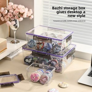 Ba hộp nhựa trong suốt xếp chồng, đựng huy hiệu trên bàn làm việc.