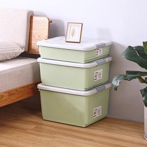 Ba hộp nhựa xanh xếp chồng cạnh giường ngủ, phù hợp lưu trữ đồ đạc.