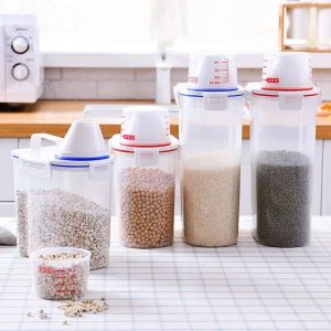 Nhiều hộp đựng thực phẩm trong suốt với cốc đong đặt trên bàn bếp.