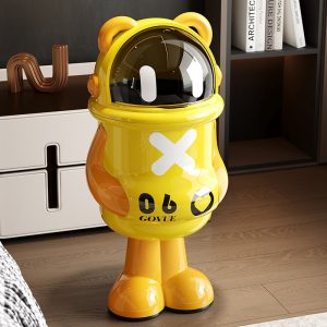 Thùng rác nhựa PP hình panda nắp lật tiện lợi dung tích lớn cho gia đình Thùng rác hình gấu panda màu vàng nổi bật đặt cạnh kệ sách.