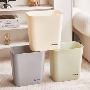 Ba thùng rác nhựa màu kem, xám và xanh nhạt đặt trong phòng khách.