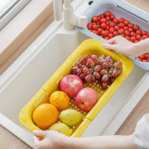Kệ nhựa màu vàng đặt trên bồn rửa, chứa trái cây như táo, nho, cam.
