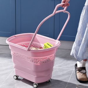 Giỏ kéo màu hồng có bánh xe, tay kéo dài, đang được sử dụng trong nhà.