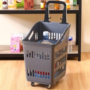 Giỏ kéo siêu thị nhựa PP cỡ lớn có bánh xe kéo tay tiện lợi Giỏ kéo siêu thị màu xám đậm, chứa chai nước lớn, đặt trên sàn gỗ.