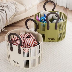 Hai giỏ đựng đồ màu kem và xanh rêu, chứa quần áo và đồ chơi trong phòng khách.