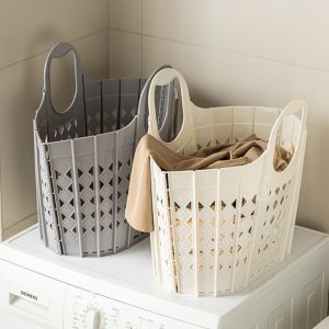 Hai giỏ nhựa lớn màu xám và trắng kem đặt trên máy giặt, chứa quần áo.