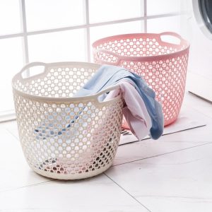 Hai giỏ đựng quần áo màu trắng và hồng đặt cạnh nhau trên sàn nhà.