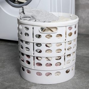 Giỏ đựng quần áo màu trắng chứa đầy quần áo, đặt trên sàn nhà.