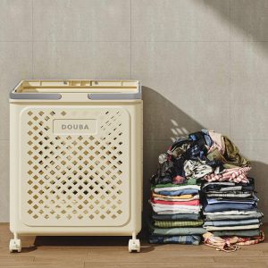 Giỏ đựng quần áo màu vàng kem đặt cạnh đống quần áo xếp gọn.