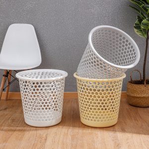 Hai giỏ đựng quần áo màu trắng và vàng nhạt đặt cạnh ghế và cây cảnh.