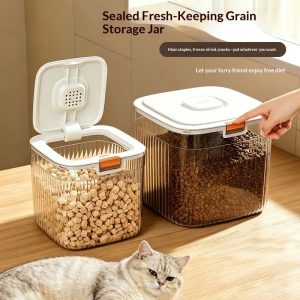 Hai hộp đựng thức ăn thú cưng, một hộp đang được mở nắp, có mèo nằm cạnh.