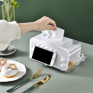 Hộp đựng khăn giấy đa năng đặt trên bàn ăn, chứa thìa dĩa và điện thoại.