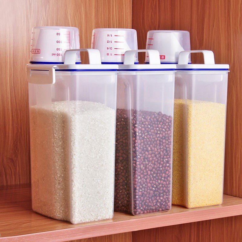 Hộp nhựa PP đựng gạo và ngũ cốc chống ẩm mốc nắp kín trong suốt Ba hộp đựng thực phẩm đặt trên kệ gỗ, chứa gạo, đậu và ngũ cốc.