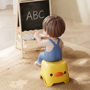 Bé trai ngồi trên ghế vịt vàng học bảng chữ cái.