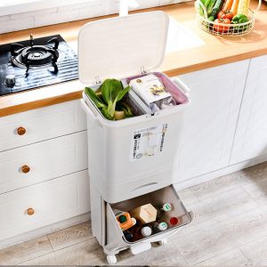 Thùng rác hai tầng đặt trong bếp, ngăn trên đựng rau củ, ngăn dưới đựng chai lọ.