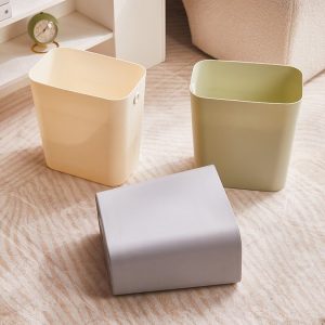 Ba thùng rác nhựa với các màu khác nhau đặt trên thảm, một cái nằm nghiêng.