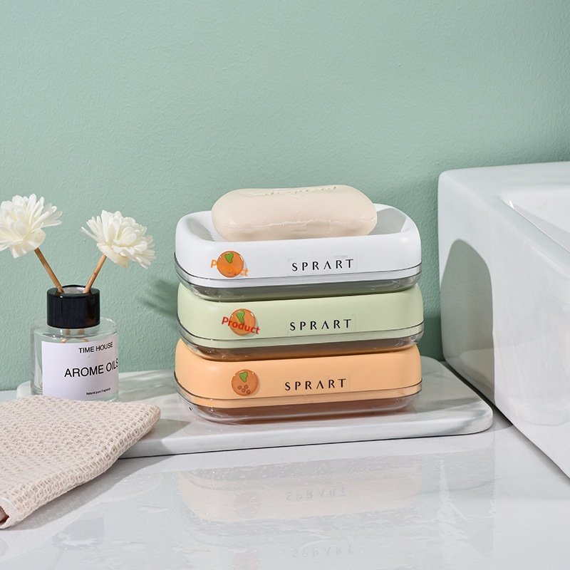 Hộp đựng xà phòng nhựa dày hai lớp thoát nước bảo quản phòng tắm Ba hộp đựng xà phòng màu trắng, xanh nhạt và cam xếp chồng lên nhau cạnh bồn rửa.