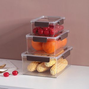 Ba hộp đựng thực phẩm xếp chồng, chứa cà chua, cam, ngô