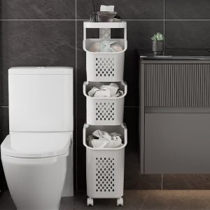 Giỏ đựng đồ 3 tầng màu trắng đặt cạnh bồn cầu, chứa quần áo và vật dụng.