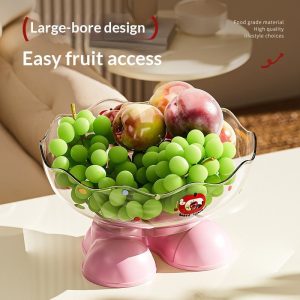 Thau nhựa trong suốt chân hồng, đựng nho xanh và mận, đặt trên bàn sáng.