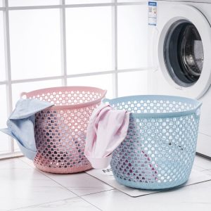 Hai giỏ đựng quần áo màu hồng và xanh dương nhạt đặt cạnh máy giặt.
