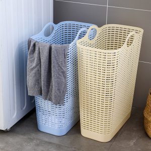 Hai giỏ đựng quần áo màu xanh dương và vàng đặt cạnh máy giặt, có khăn treo.