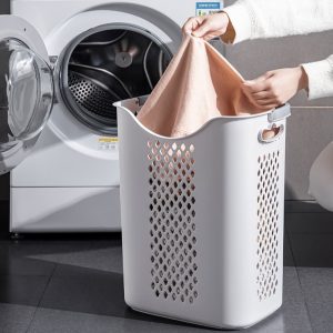 Người dùng bỏ quần áo vào giỏ trước máy giặt.