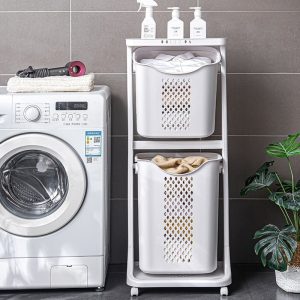 Giỏ đựng quần áo hai tầng đặt cạnh máy giặt, phía trên có chai lọ và khăn