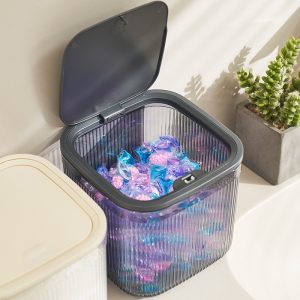 Hộp nhựa nắp xám mở, bên trong đựng viên giặt nhiều màu sắc.