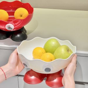 Cận cảnh khay trắng chân đỏ, đang được cầm, đựng táo và cam.