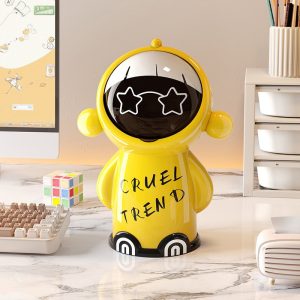 Thùng rác mini để bàn nhựa PP 5L hình hoạt hình đa năng cho gia đình Thùng rác mini màu vàng đặt trên bàn làm việc cạnh máy tính và rubik.
