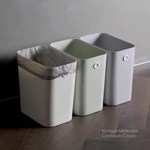 Ba thùng rác nhựa đặt sát tường, một thùng đã lắp túi rác.