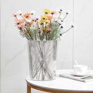 Thùng rác nhựa trong suốt được dùng cắm hoa trang trí trên bàn.