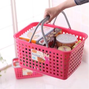 Người cầm giỏ nhựa màu hồng, bên trong đựng nhiều thực phẩm và đồ dùng.