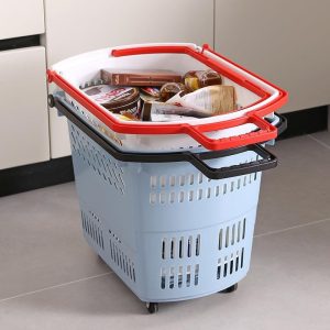 Giỏ kéo nhựa PP đa năng đi chợ có bánh xe, tay kéo tiện lợi 50L Giỏ nhựa xanh nhạt với tay cầm đỏ, chứa nhiều thực phẩm, đặt trên sàn nhà.