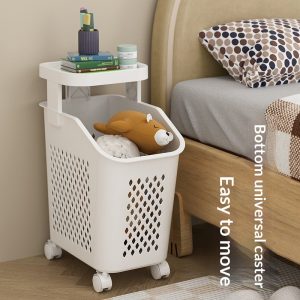 Giỏ đựng đồ một tầng, có bánh xe, đặt cạnh giường với thú bông và sách