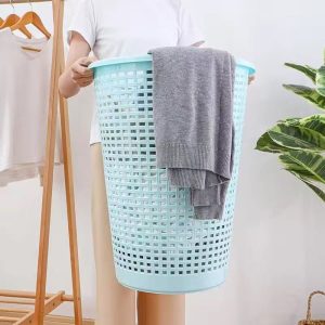 Người cầm giỏ đựng quần áo màu xanh lớn, bên trong có quần áo.