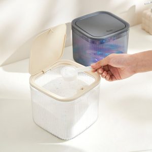 Hộp nhựa nắp be mở, có thìa múc bột giặt bên trong.