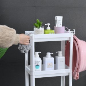 Cận cảnh tầng trên cùng của kệ nhựa với các chai lọ và móc treo khăn.