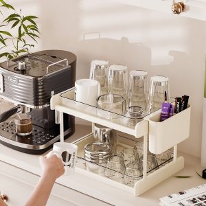 Kệ đựng cốc hai tầng đặt cạnh máy pha cà phê, chứa nhiều ly thủy tinh và phụ kiện pha chế.