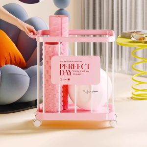 Giỏ nhựa có bánh xe đựng thảm yoga, đồ chơi, dụng cụ tập thể dục đa năng Giỏ đựng màu hồng chứa thảm yoga và bóng, đặt cạnh ghế sofa.