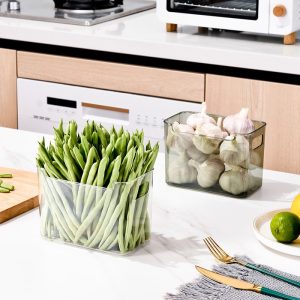 Hai hộp nhựa đựng đậu que và tỏi đặt trên bàn bếp.