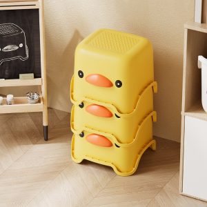 Ba ghế đẩu vịt vàng được xếp chồng lên nhau sát tường.