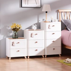 Tủ nhựa đặt cạnh giường, trang trí với hoa và đèn ngủ.