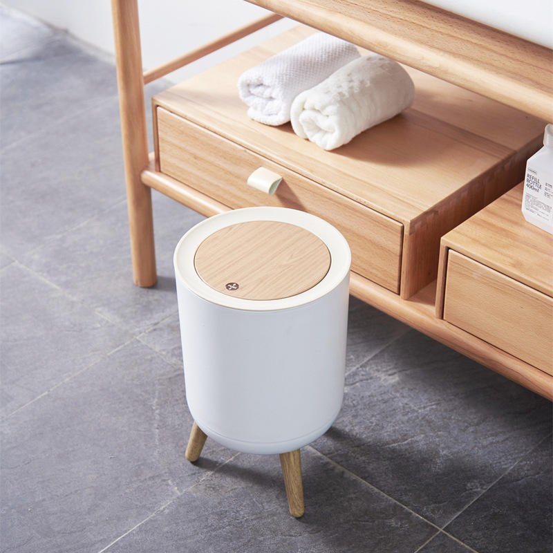 Thùng rác mini nhựa PP nắp lật vân gỗ phong cách Nhật cho phòng ngủ, phòng tắm Thùng rác mini chân gỗ đặt cạnh tủ gỗ, nhìn từ trên xuống.