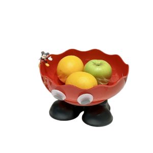 Khay đỏ hình chân cao, đựng cam và táo, có tượng nhỏ trang trí.